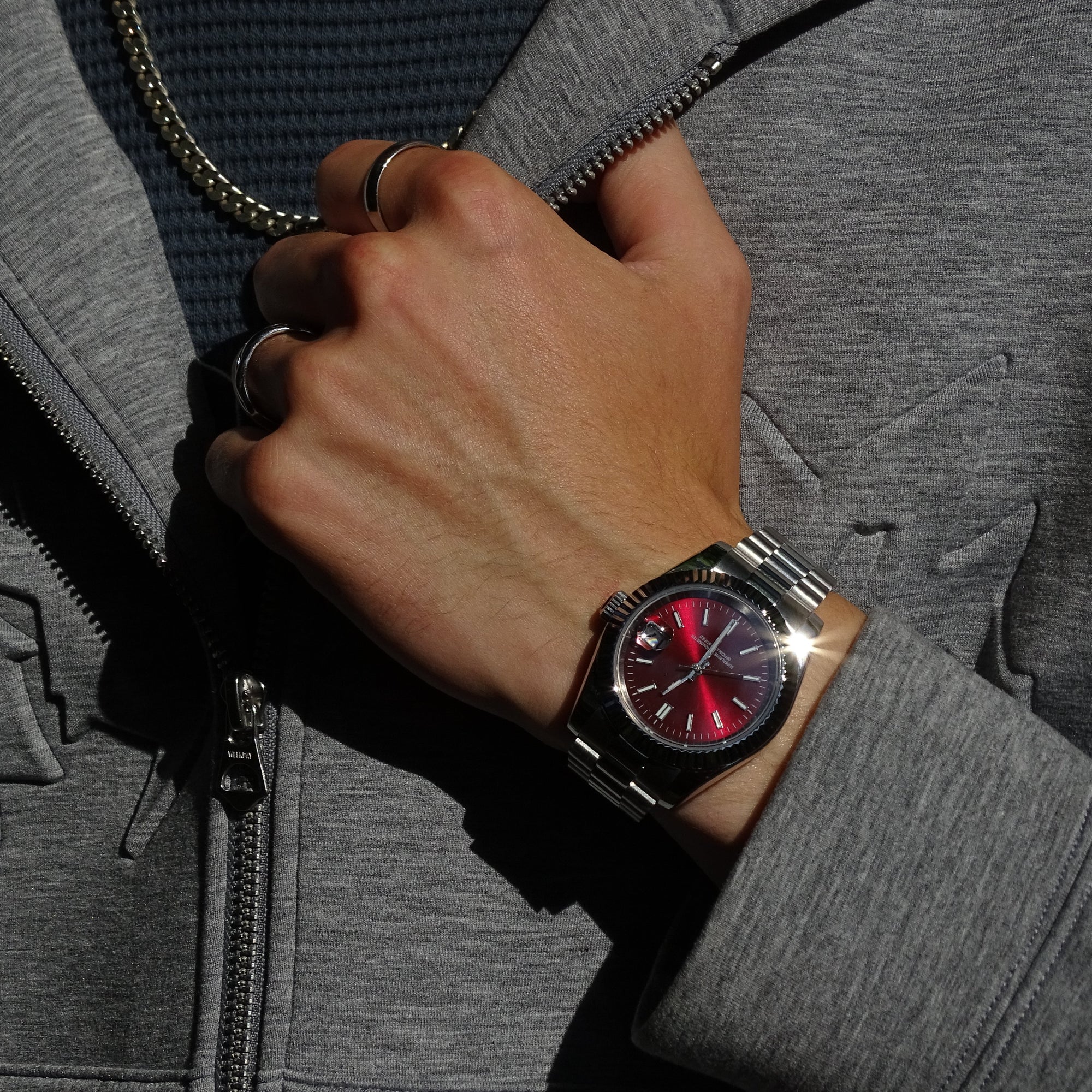 Elusivy watch on wrist with chain and chrome red dial